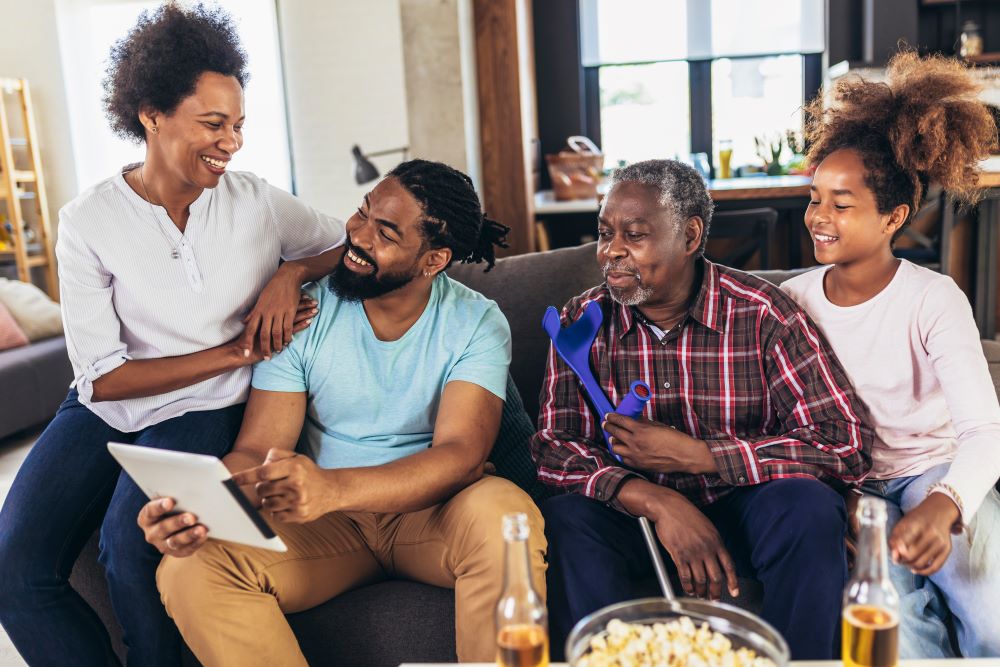 Portrait of multi generation family sitting in living room and using digital tablet
