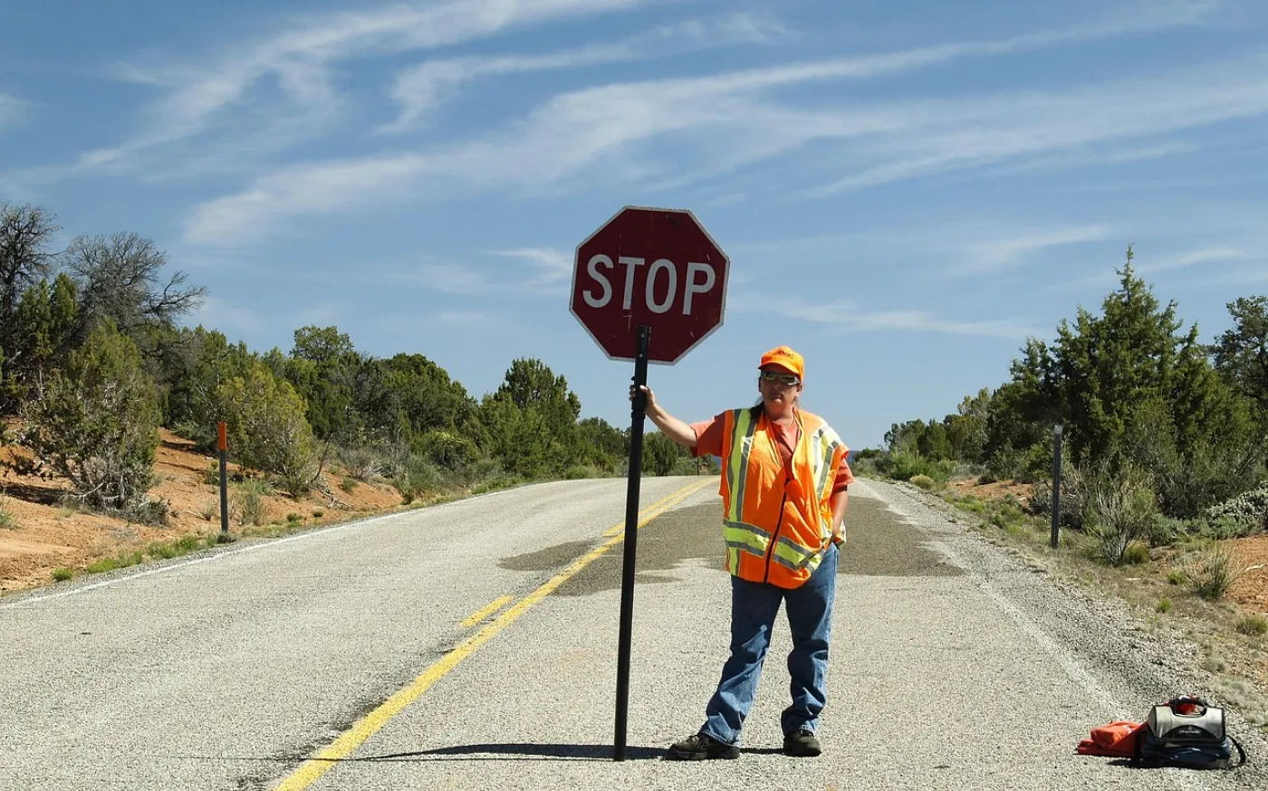 a construction worker standing on a road holding a stop sign
