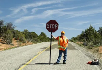 a construction worker standing on a road holding a stop sign