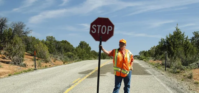 a construction worker standing on a road holding a stop sign